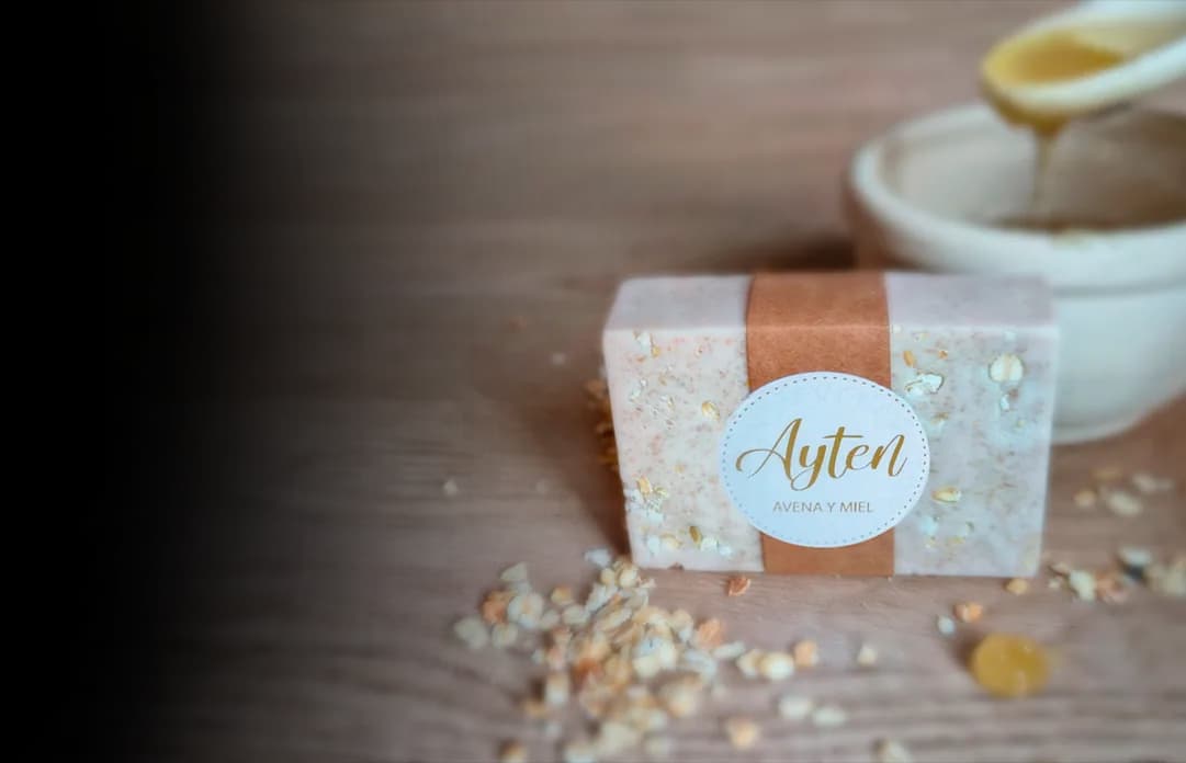 Jabón de avena y miel de Ayten sobre una mesa de madera, junto a un bol de miel y avena